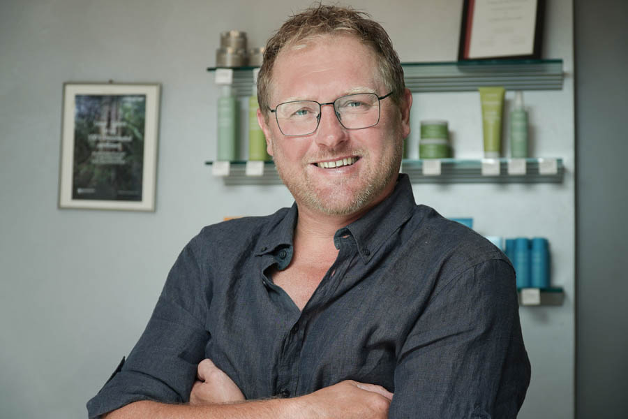 Porträt Christian Erntl vor Regalen mit Haarpflegeprodukten.